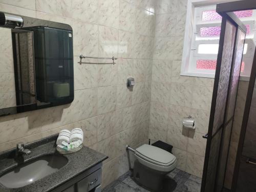 łazienka z toaletą, umywalką i lustrem w obiekcie Casa temporada w mieście Joinville