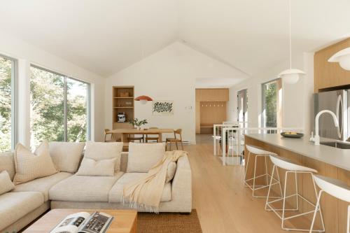 a living room with a white couch and a kitchen at Maison Solus - Mont Tremblant in Lac-Superieur