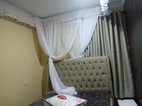 Schlafzimmer mit einem Bett mit Baldachin und Vorhängen in der Unterkunft Rosslyn suites in Juja