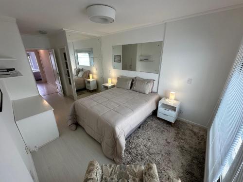 Duplex Por do Sol a Beira Mar في فلوريانوبوليس: غرفة نوم بيضاء مع سرير وأريكة