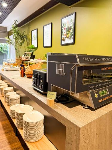 a kitchen counter with a toaster oven and plates at Noa Hotel in Auckland