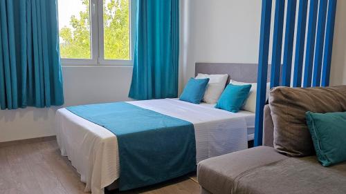 a bedroom with a bed with blue curtains and a couch at Zero Distance Studio in Podgorica