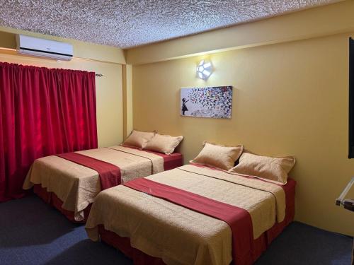 AroucaJaycees Place的配有红色窗帘的客房内的两张床