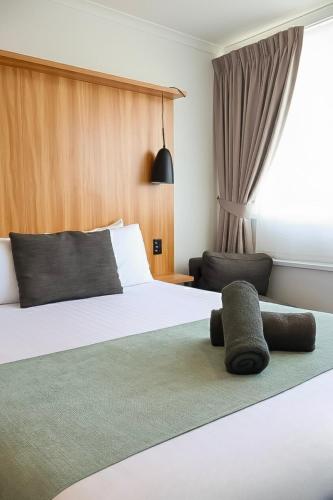 a hotel room with a bed and a chair at Noa Hotel in Auckland