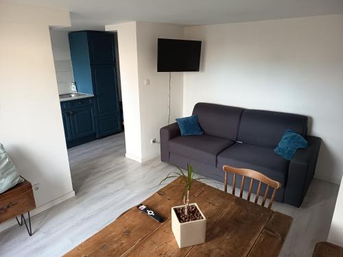 a living room with a couch and a table at Beau studio à 2mn de la mer et avec jardin in Bray-Dunes