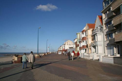 a group of people walking down a street near the beach at Beau studio à 2mn de la mer et avec jardin in Bray-Dunes