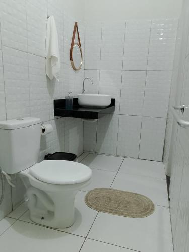 a white bathroom with a toilet and a sink at hospedaria Cantinho da Rosa in Santo Amaro