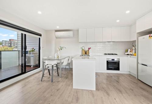 a kitchen with white cabinets and a table with chairs at Bright Home Travel Service at Mt Albert in Auckland
