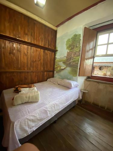 a bedroom with a bed with a painting on the wall at Pousada Matriz in São Thomé das Letras