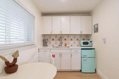 a kitchen with white cabinets and a green refrigerator at THE JUNI - Studio Steps to Beach Downtown in Cocoa Beach