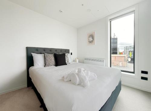 sypialnia z białym łóżkiem i pluszowym zwierzątkiem na nim w obiekcie City life Skytower view With Swimming pools & Suna Family Retreat w Auckland