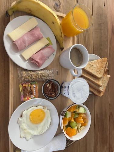 a table topped with plates of breakfast food and a banana at Chambre et Bungalow confort vue piscine in Baie-Mahault