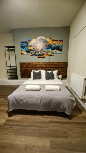 a bedroom with a large bed with three paintings on the wall at City Stays Norwich in Norwich