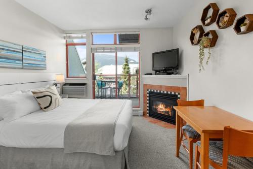a bedroom with a bed and a desk and a fireplace at Alpenglow Lodge by MVA in Whistler