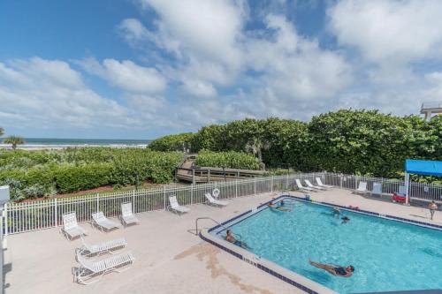 a swimming pool with chairs and a beach at Beachside Oasis at Villages of Seaport in Cape Canaveral