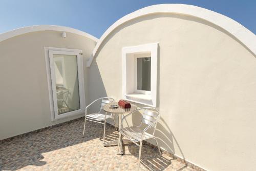 two chairs and a table on a balcony with two windows at Asterolithos in Fira