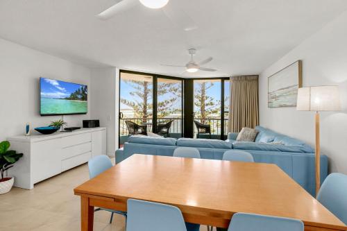 a living room with a blue couch and a table at Eastbourne U6 80 Esplanade Golden Beach in Caloundra
