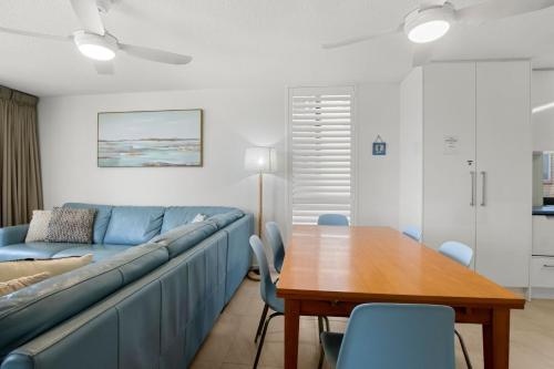 a living room with a blue couch and a wooden table at Eastbourne U6 80 Esplanade Golden Beach in Caloundra