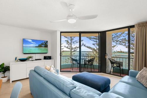 a living room with a blue couch and a balcony at Eastbourne U6 80 Esplanade Golden Beach in Caloundra