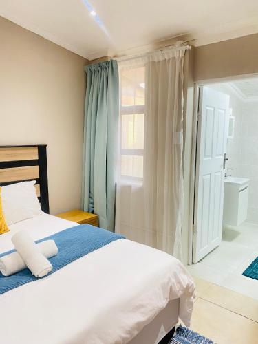 a bedroom with a white bed and a bathroom at EThembeni Guesthouse in Gqeberha