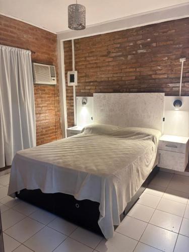 ein Schlafzimmer mit einem großen Bett mit Ziegelwand in der Unterkunft Excelente Casita en Paso in Paso de la Patria
