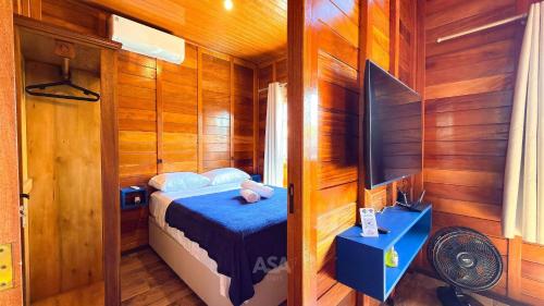 um pequeno quarto com uma cama e uma televisão em ASA | Chalés Vô Luiz | 2QT | Ar Cond. | Churrasqueira | Próx. à Praia em Gravata