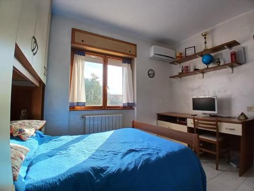 1 dormitorio con cama azul, escritorio y ventana en Casa di Viaggiatori Ciampino, en Ciampino