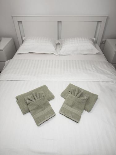 a white bed with two green towels on it at Luxury Avantgarden apartament in Braşov