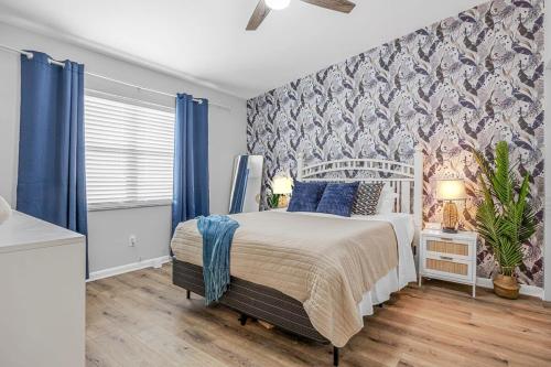 a bedroom with a large bed with blue curtains at Downtown Cocoa Beach Townhome- Walk to Everything in Cocoa Beach