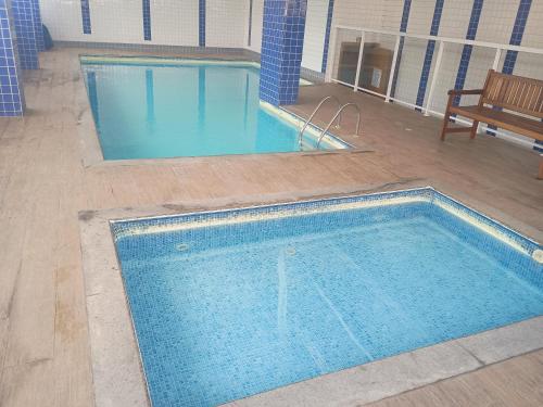an empty swimming pool in a building with a bench at Apto Pe na areia # Piscina e Churrasqueira in Mongaguá