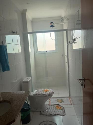 a white bathroom with a shower and a toilet at Apto Pe na areia # Piscina e Churrasqueira in Mongaguá