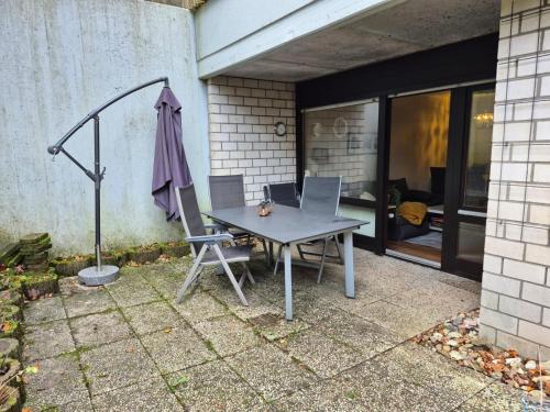 a table with chairs and an umbrella on a patio at Uni- und Citynahe Souterrain-Wohnung am Waldpark in Wuppertal