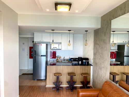 a kitchen with a refrigerator and a counter with stools at Porto Real Resort Apto luxo de frente ao mar in Mangaratiba