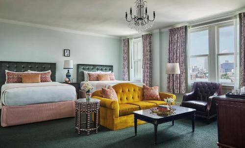 ein Schlafzimmer mit einem Bett, einem Sofa und einem Kronleuchter in der Unterkunft Pontchartrain Hotel St. Charles Avenue in New Orleans