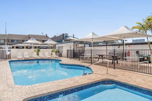 a pool with umbrellas and chairs and a table at Absolute Beachfront Apartment 4T in Lennox Head