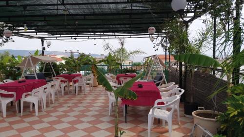 a restaurant with red tables and white chairs and plants at La Fontaine Apartments in Kandia