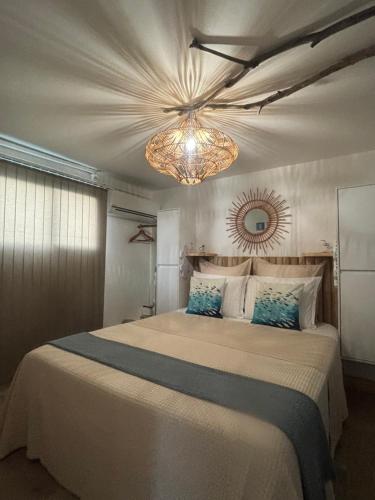 a bedroom with a large bed with a chandelier at Appartement vue mer, Case Pilote in Case-Pilote