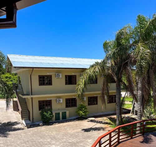 a building with palm trees in front of it at Pousada Samburá in Garopaba