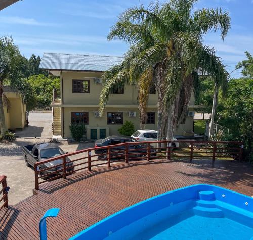 a swimming pool in front of a house with a palm tree at Pousada Samburá in Garopaba