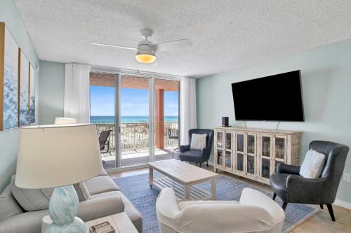 a living room with a tv and a couch and chairs at Buena Vista 102 in Gulf Shores