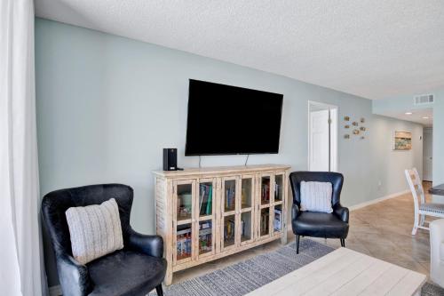 a living room with two chairs and a flat screen tv at Buena Vista 102 in Gulf Shores