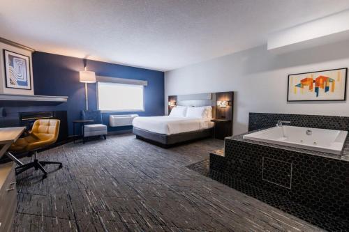 a hotel room with a bed and a bath tub at Holiday Inn Express Calgary South by IHG in Calgary