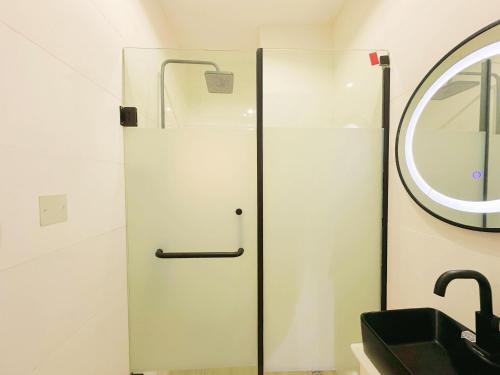 a bathroom with a glass shower door next to a sink at LinQues & Bethel Residences in Ibadan