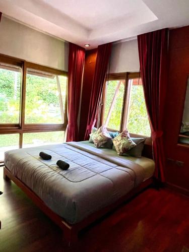 a bedroom with a large bed with windows at Panoramic sea view flat, overlooking Bang Bao in Ban Bang Bao