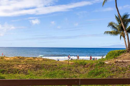 a beach with palm trees and people on the beach at Affordable Vacation Accommodations in Maui at the Kihei Kai Nani Resort in Kihei