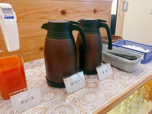 due bollitori sono appoggiati su un tavolo con cartelli dei prezzi di ホテル韮崎インター a Nirasaki