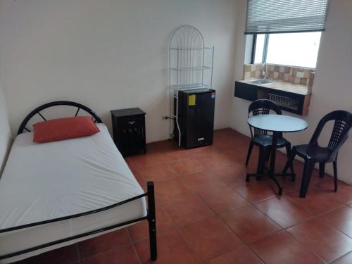 een slaapkamer met een bed, een tafel en stoelen bij Casa #4 Studios in San Pedro