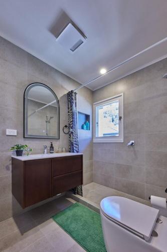 a bathroom with a toilet and a sink and a mirror at Stylish 2BR Family-Friendly Retreat 4Guests Doncaster Westfield in Doncaster
