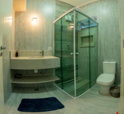 een badkamer met een glazen douche en een toilet bij O paraíso em Peruíbe Casa para até 25 pessoas in Peruíbe
