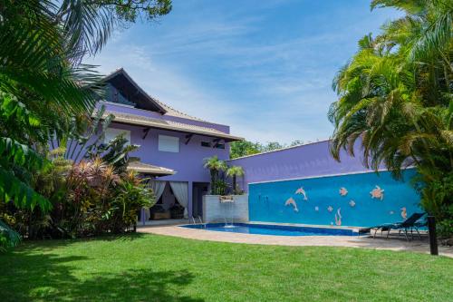 een huis met een blauwe muur en een zwembad bij O paraíso em Peruíbe Casa para até 25 pessoas in Peruíbe